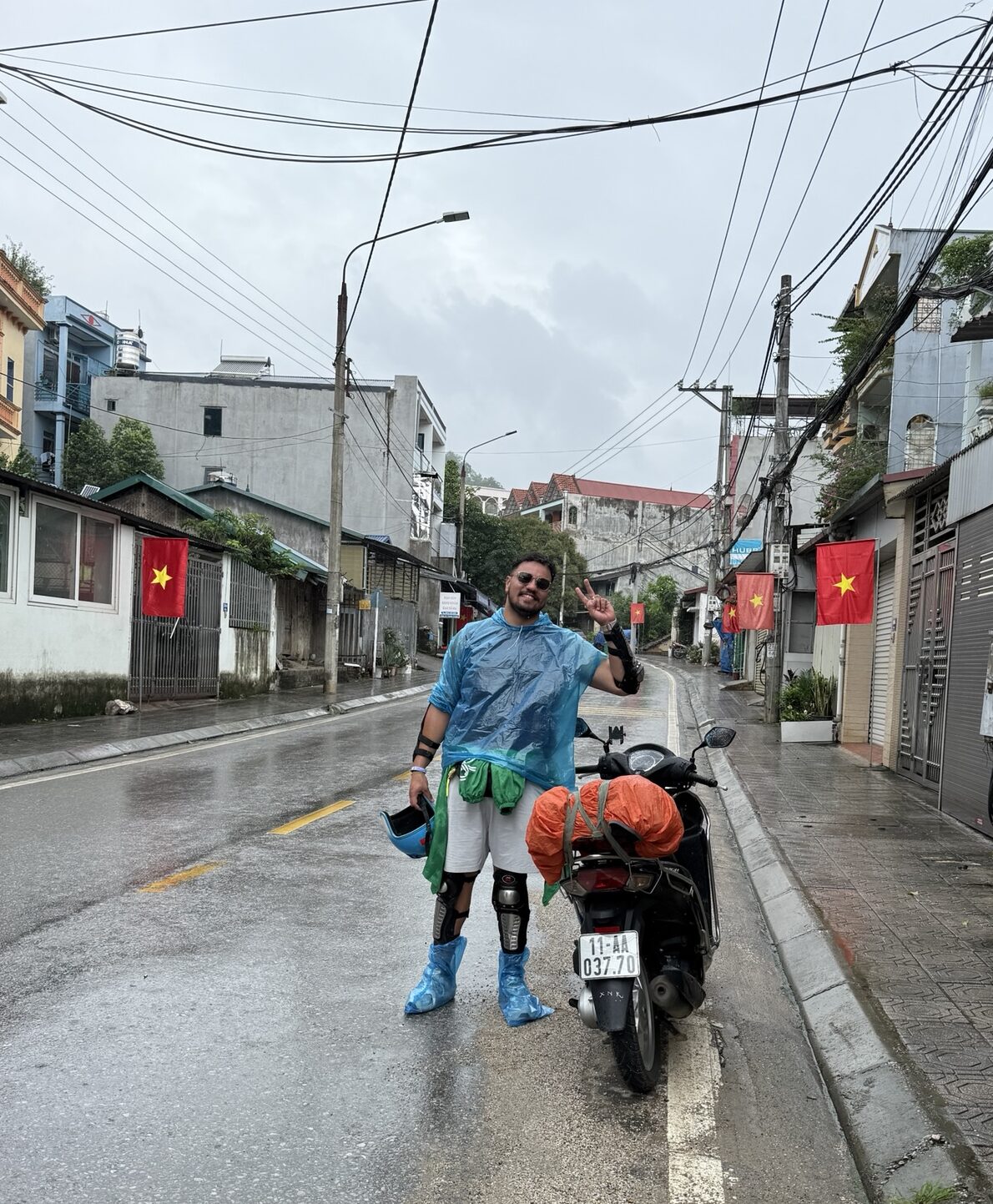 Voyageuse en tenue de pluie complète à côté de son scooter avant de partir sur la boucle de Cao Bang