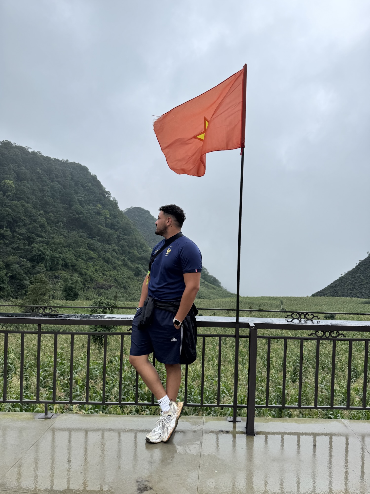 Voyageuse devant le drapeau vietnamien à la frontière chinoise, boucle de Ha Giang